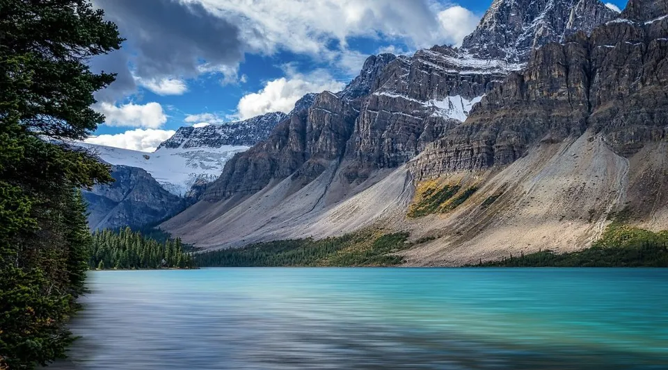 Un lago montano turchese di fronte a ripide rocce innevate e boschi nella regione della Daysland School.