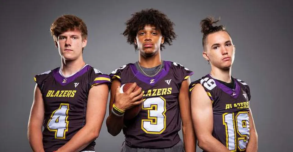 Tre studenti della Durango High School indossano le maglie da calcio dei Blazers davanti a uno sfondo grigio.