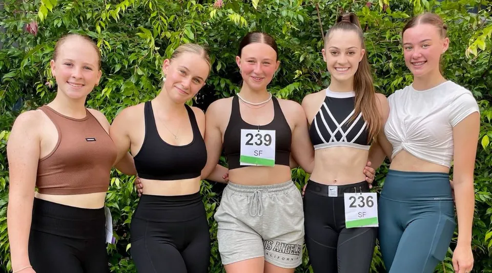 Un gruppo di cinque studentesse in abbigliamento sportivo si trova nell'area verde esterna della Kingaroy State High School.