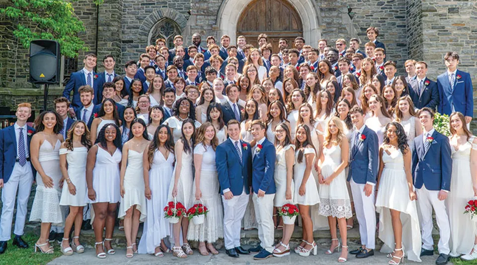 Un gruppo di studenti vestiti in modo formale si raccoglie davanti a una chiesa in pietra sul campus di The Masters School.