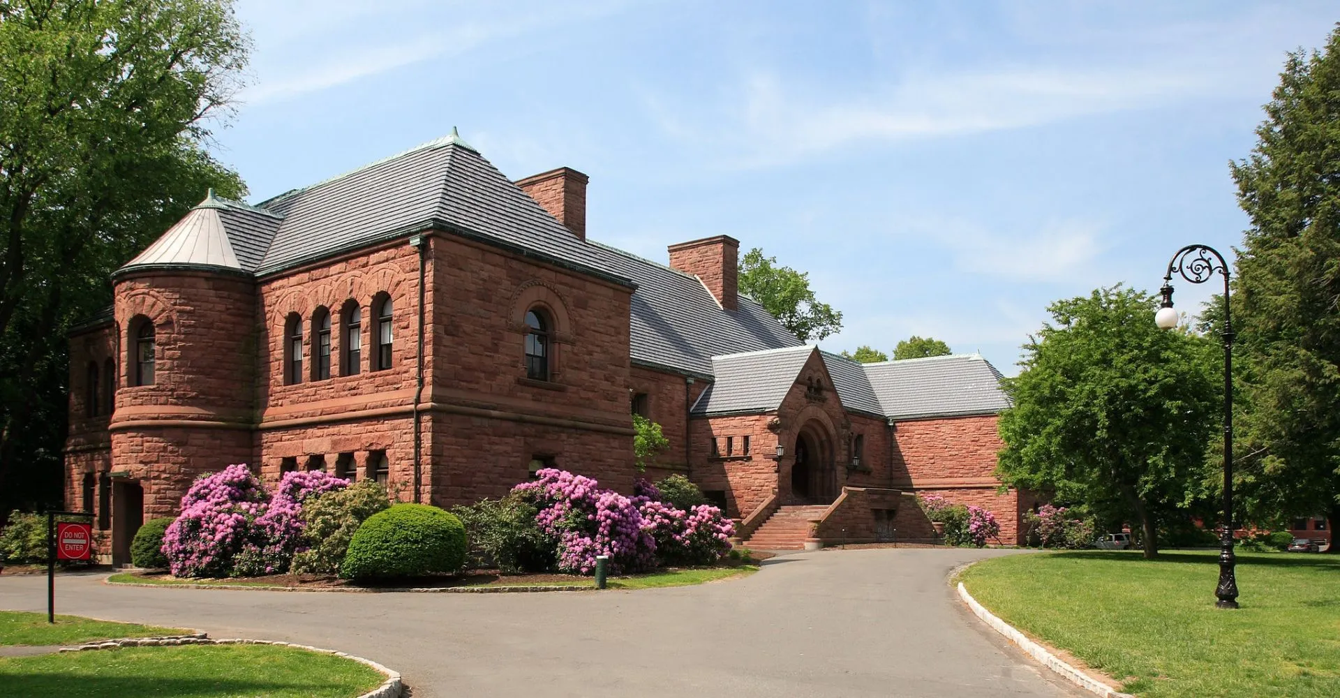 L'edificio storico in pietra rossa della The Lawrenceville School circondato da cespugli fioriti e prati.