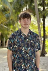 Ramon in camicia a fantasia tropicale sorride davanti alle palme durante il suo anno all'estero