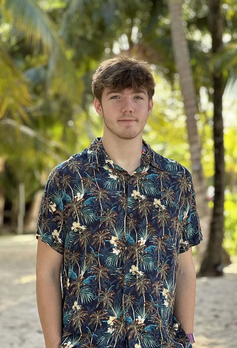 Ramon in camicia a fantasia tropicale sorride davanti alle palme durante il suo anno all'estero