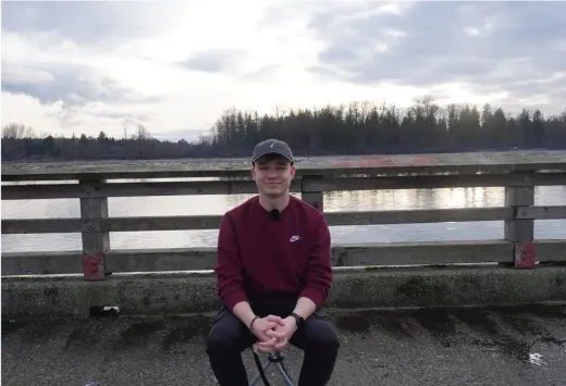 Stefan sitzt auf einem Geländer vor einem Fluss in Kanada