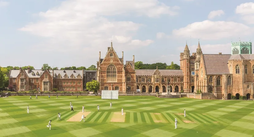 Studenti giocano a cricket sul prato davanti agli storici edifici neogotici del Clifton College.