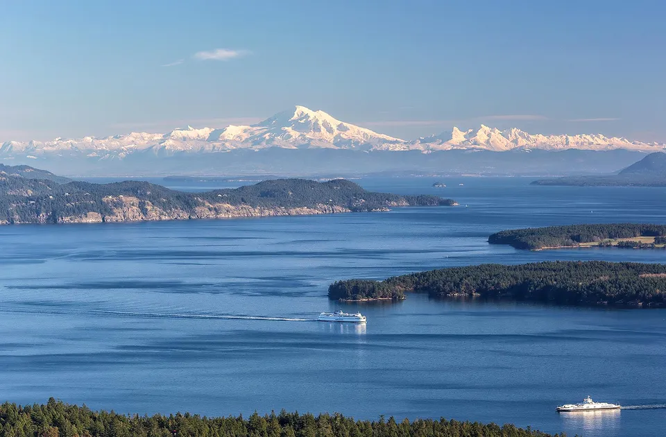 Vista su uno specchio d'acqua calmo con isole boscose e montagne innevate sullo sfondo vicino alla Gulf Islands Secondary School.