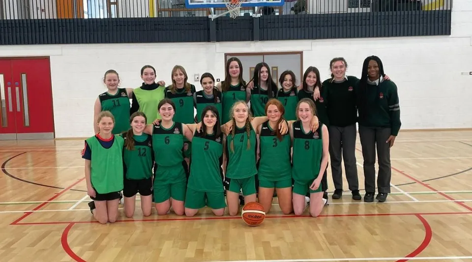 Un gruppo di giovani giocatrici di basket del St. Colman’s Community College posa insieme sul campo da basket.