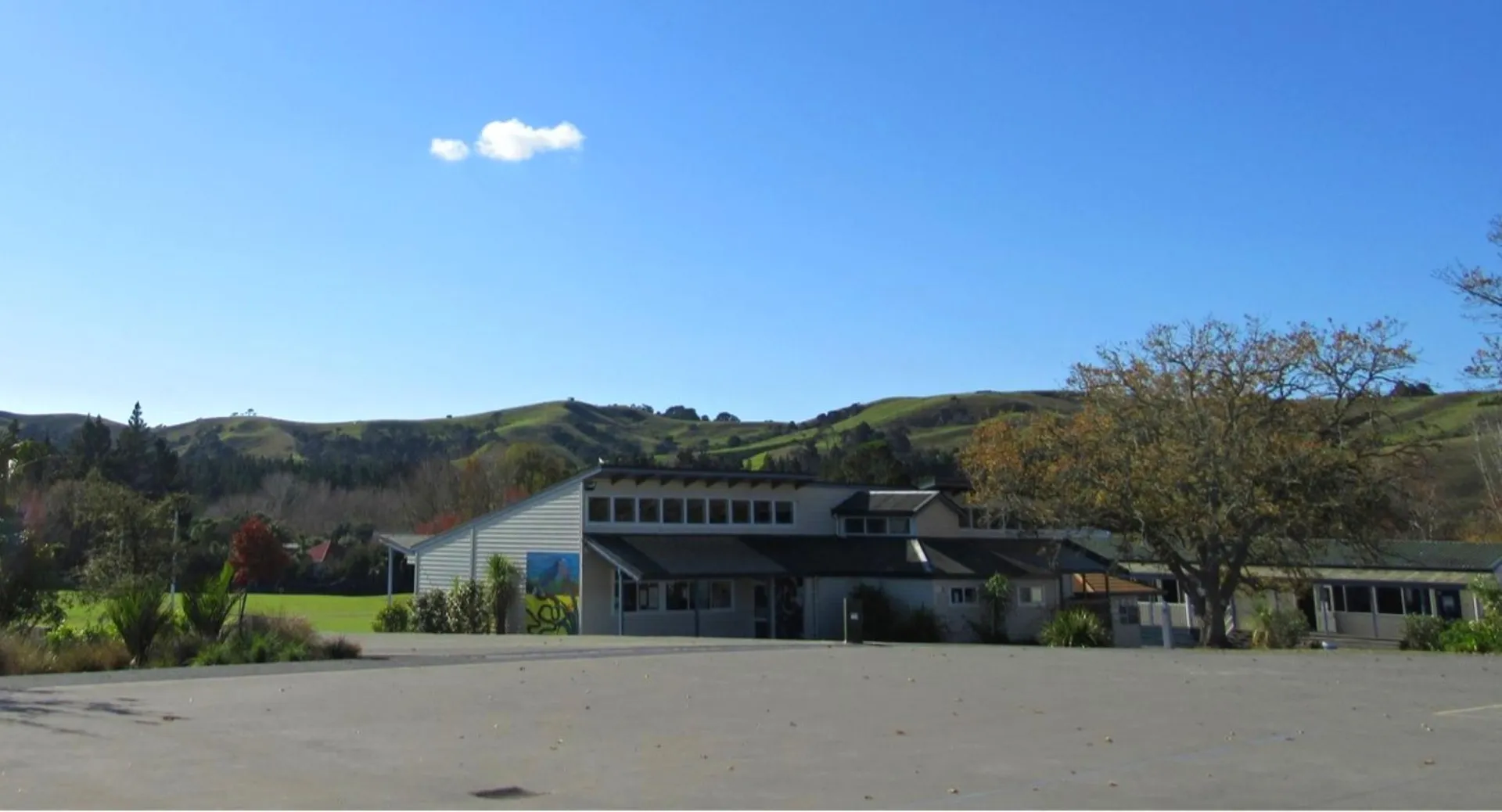 L'edificio bianco del Kaipara College si trova incastonato tra dolci colline e un paesaggio verde sotto un cielo azzurro.