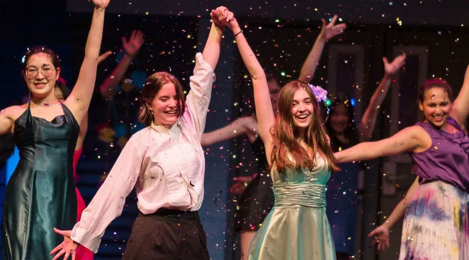 Un gruppo di giovani donne danza sul palco della Northfield Mount Hermon School davanti a uno sfondo scintillante.