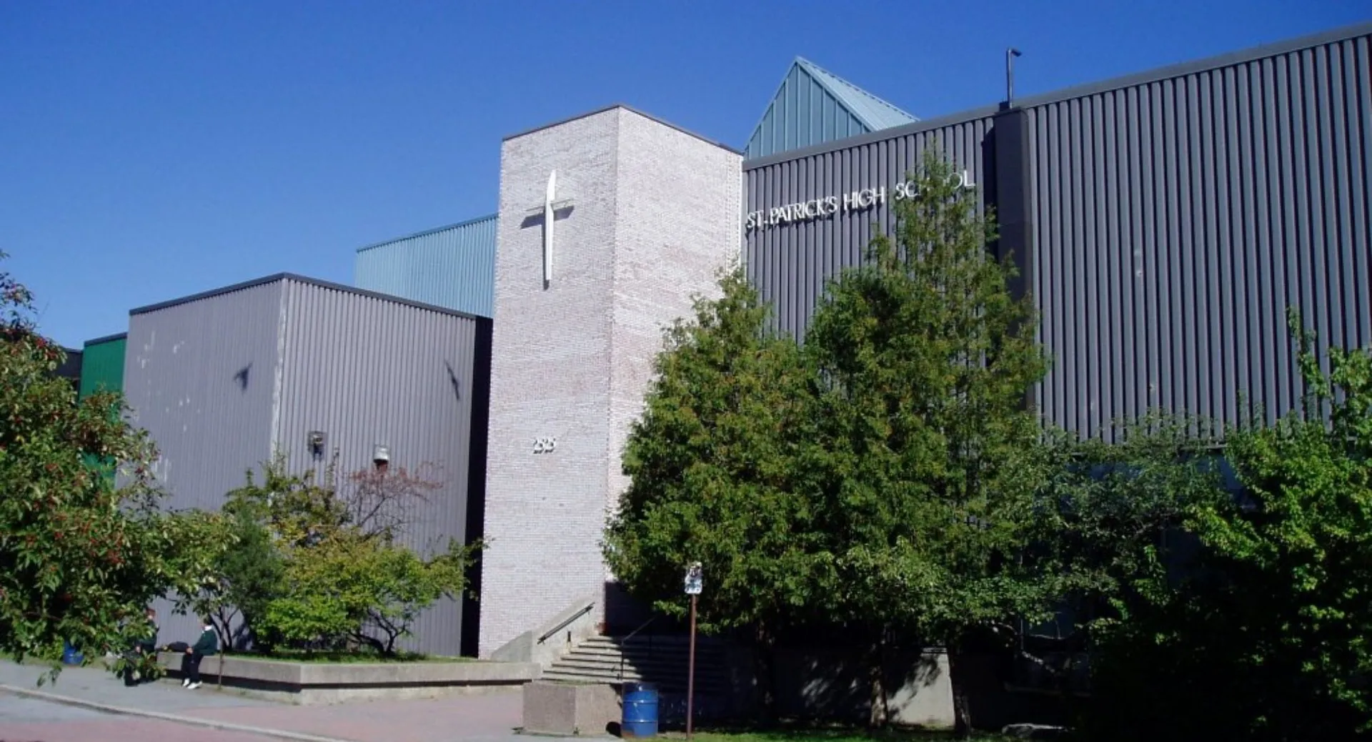 L'edificio moderno a più piani della St. Patrick's High School è circondato da una verde vegetazione sotto un cielo azzurro e limpido.