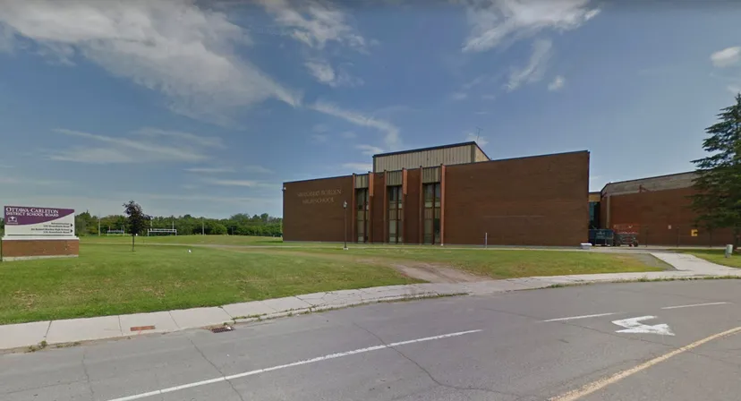L'edificio in mattoni della Sir Robert Borden High School sorge su un'area verde sotto un cielo azzurro con nuvole.