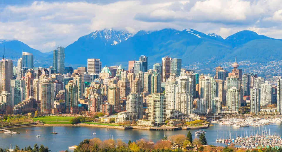 Panorama dello skyline di Vancouver con grattacieli, un porto turistico e montagne innevate nei pressi della West Vancouver Secondary.