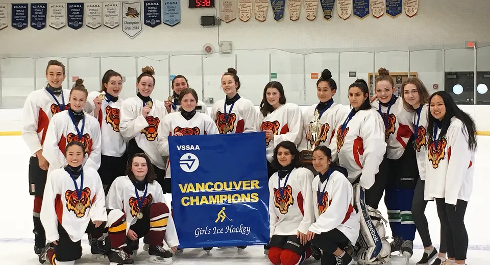 Un gruppo di giocatrici di hockey della Sir Charles Tupper Secondary School tiene uno striscione con la scritta Vancouver Champions.