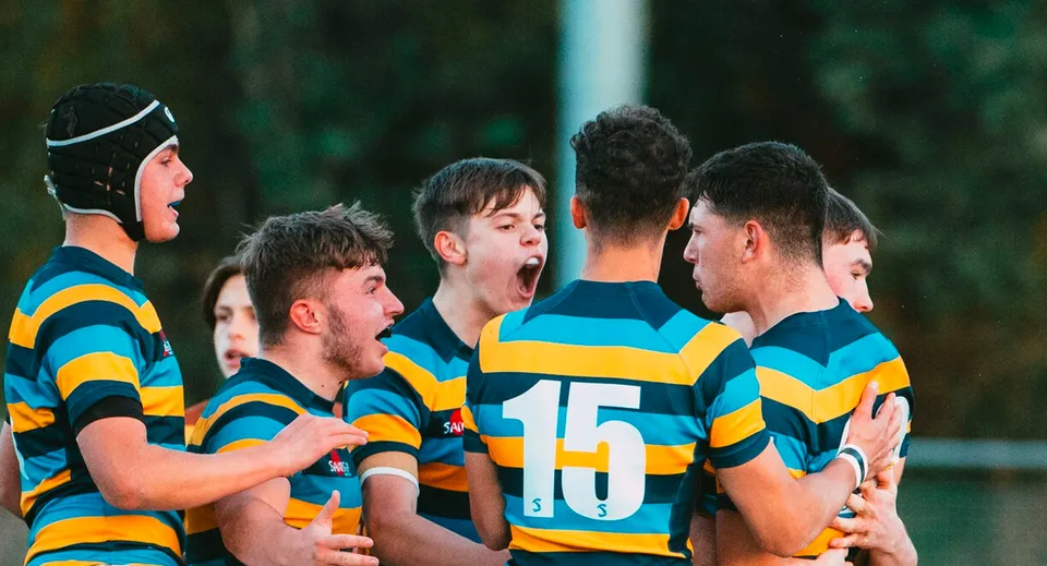Un gruppo di studenti che gioca a rugby in maglia colorata si tiene stretto sul terreno del Mount St. Mary's College.