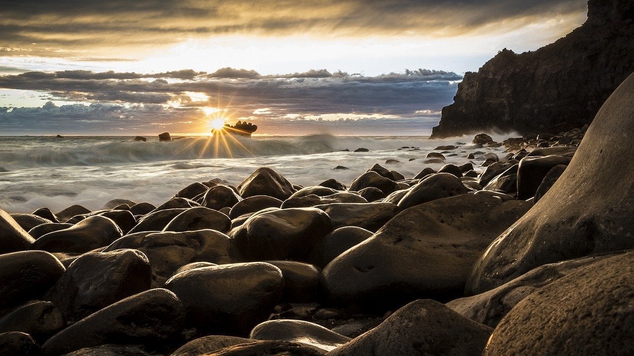 Runde Steine an einer Felsküste bei Sonnenuntergang über dem Meer