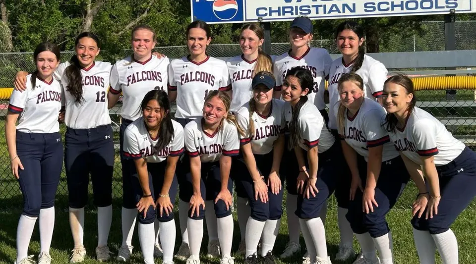 Un gruppo di studentesse della Vacaville Christian School posa con le divise da softball davanti all'insegna della scuola.