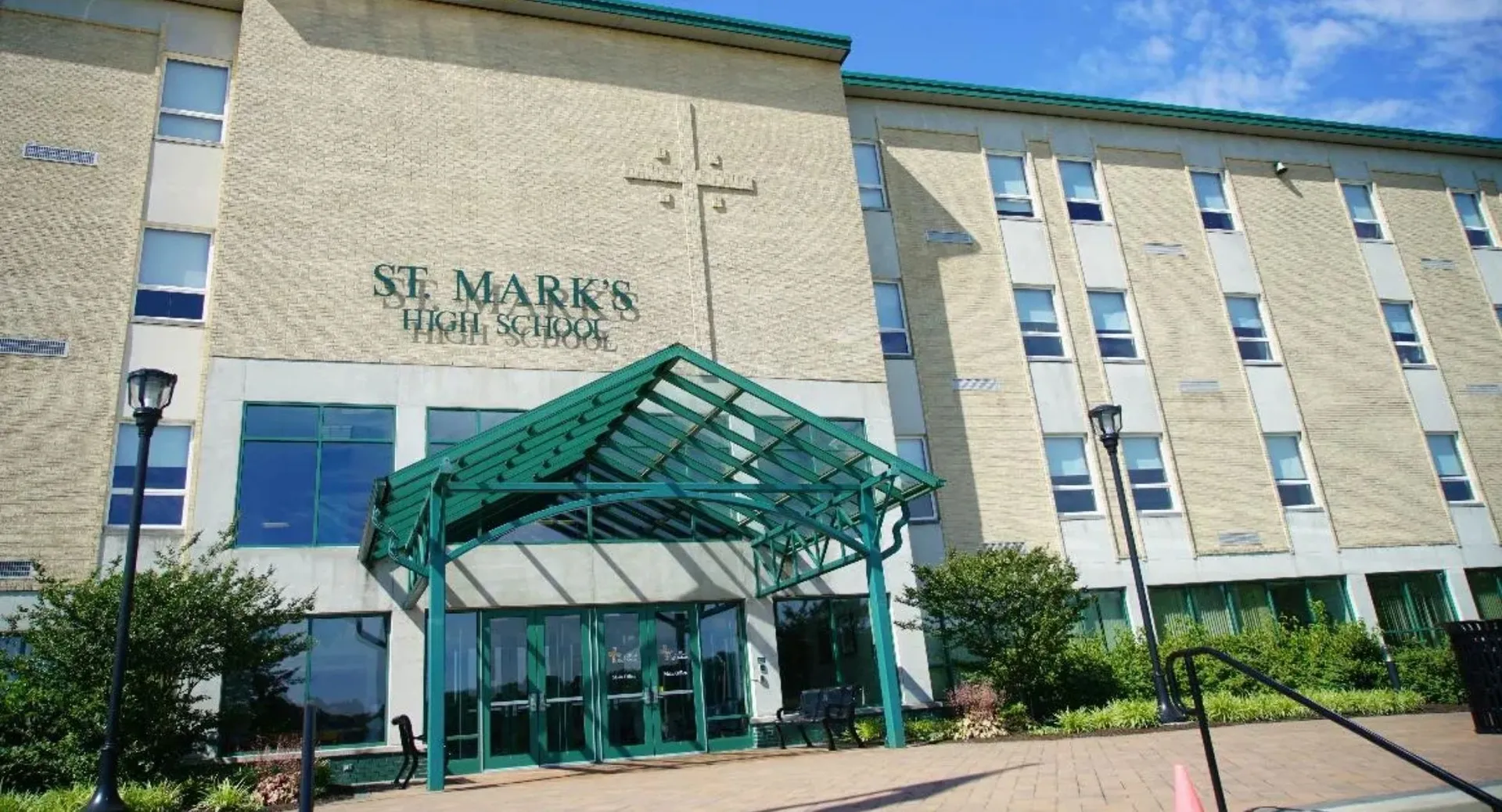 L'edificio in mattoni a più piani con l'ingresso in vetro verde appartiene alla St. Mark High School ed è circondato da alberi.