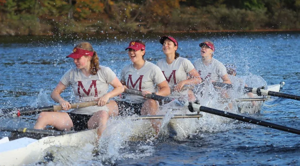 Quattro studentesse e studenti della Marianapolis Preparatory School remano su un lago circondato da vegetazione autunnale.