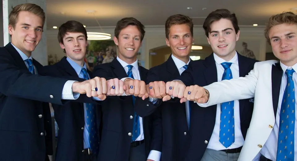 Un gruppo di giovani ragazzi in giacca e cravatta dell'Upper Canada College mostra la propria unione unendo i pugni.