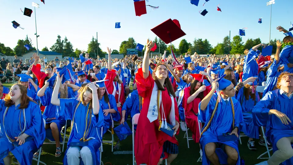 Studenti della Winston Churchill High School indossano tocco e toga da diploma durante una cerimonia all'aperto.