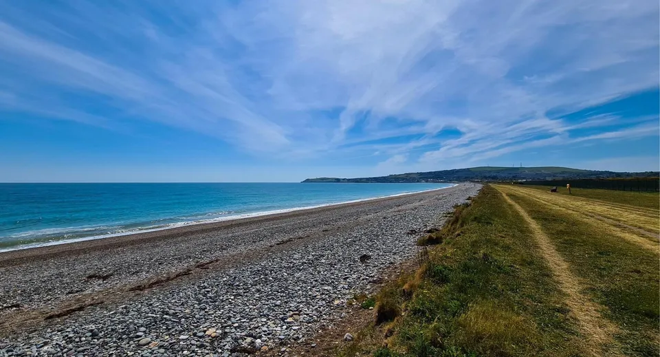 Un paesaggio costiero con spiaggia di ciottoli e un sentiero erboso vicino alla Coláiste Chill Mhantáin.