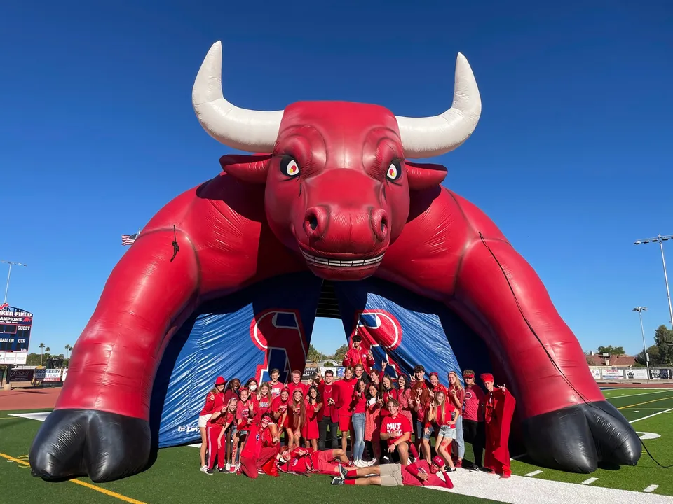 Un gruppo di studenti della Mountain View High School si trova sul campo sportivo con la mascotte del toro rosso.