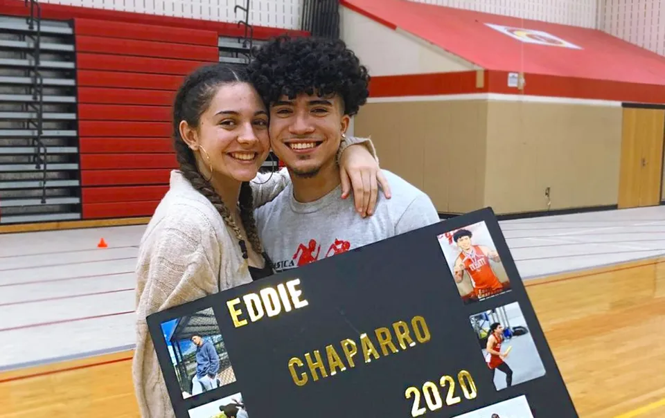 Una giovane coppia in posa insieme davanti a un poster con il nome Eddie Chaparro nel campus della Mount Everett Regional High School.