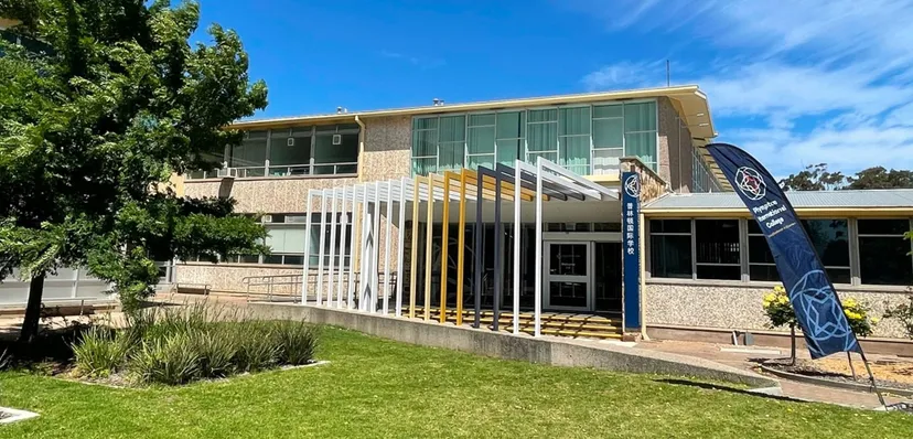 L'edificio moderno a più piani con facciata in vetro e area verde nel campus del Plympton International College.