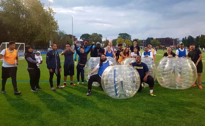 Un grupo de estudiantes de la Central Technical School lleva Bubble-Suits inflables en un césped.