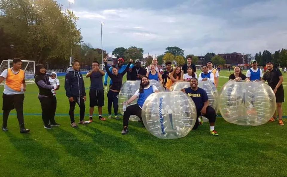 Un gruppo di studenti della Central Technical School indossa tute gonfiabili bubble suit su un prato.