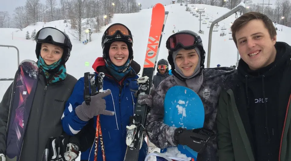 Un gruppo di studenti della Leelanau School si trova su una pista innevata, equipaggiato con casco e occhiali da sci.