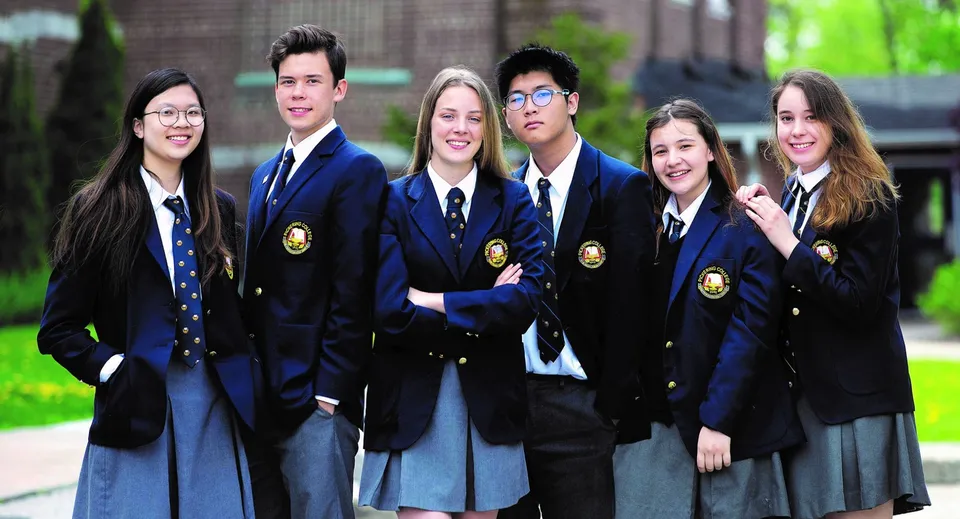Un gruppo di studenti in uniforme scolastica si trova davanti a un edificio nel campus del Pickering College.