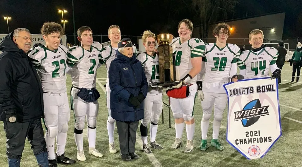 I giocatori di calcio dell'Institut Collégial Vincent Massey Collegiate tengono un trofeo sul campo di gioco di notte.