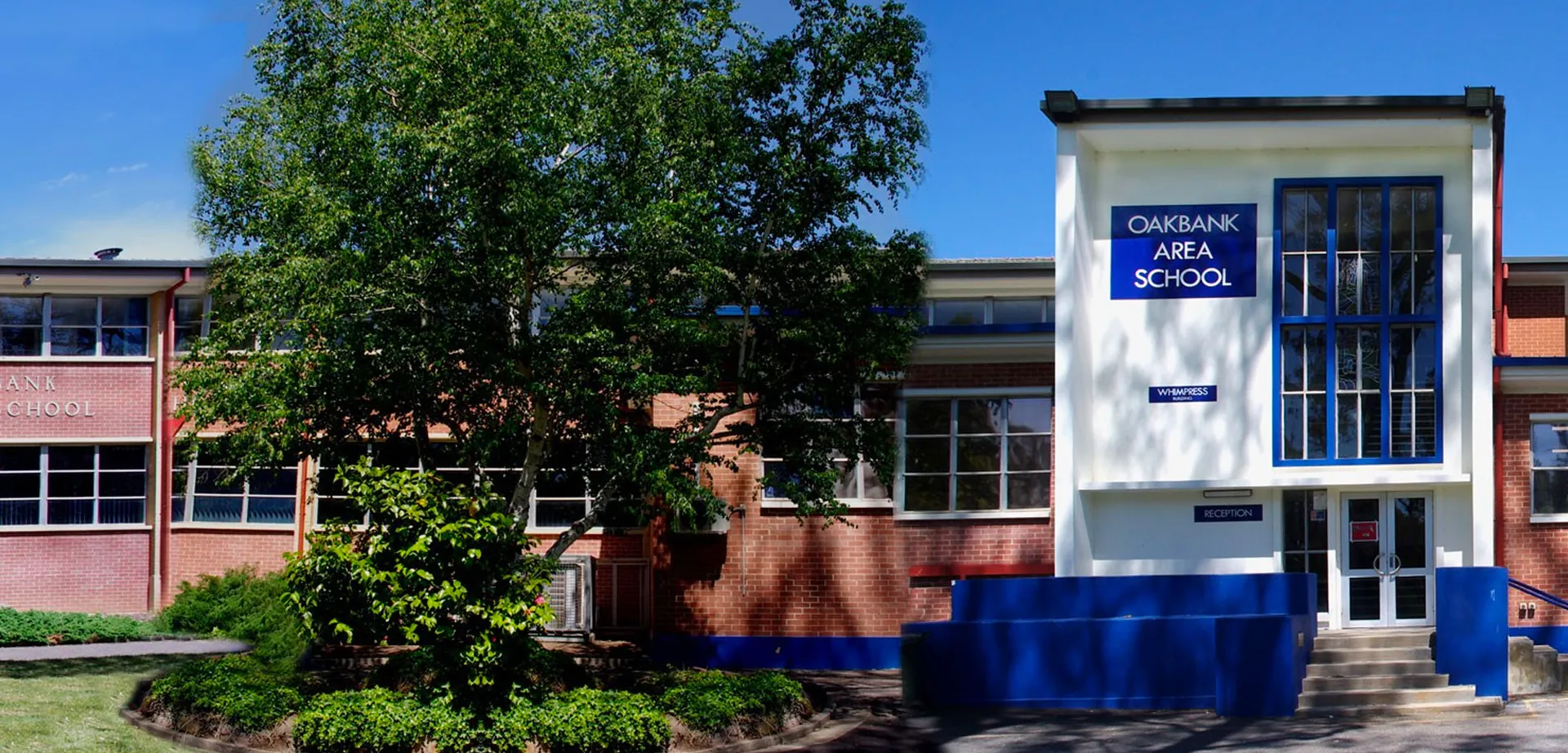 L'edificio in mattoni della Oakbank Area School è circondato da alberi e aree verdi.