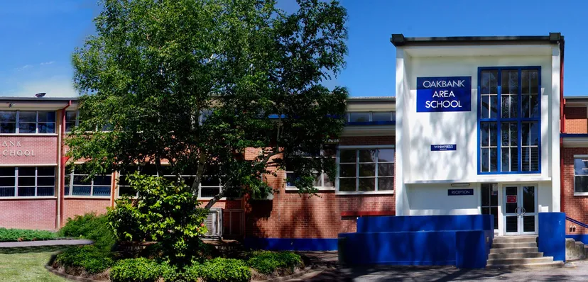 L'edificio in mattoni della Oakbank Area School è circondato da alberi e aree verdi.