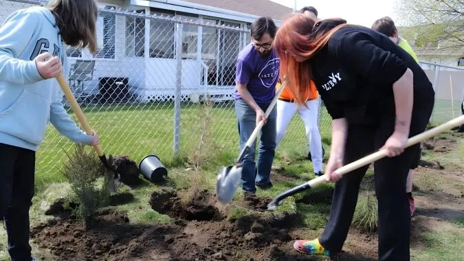 Estudiantes de la A.L. Fortune Secondary School cavan juntos agujeros en el suelo para una acción de plantación al aire libre.