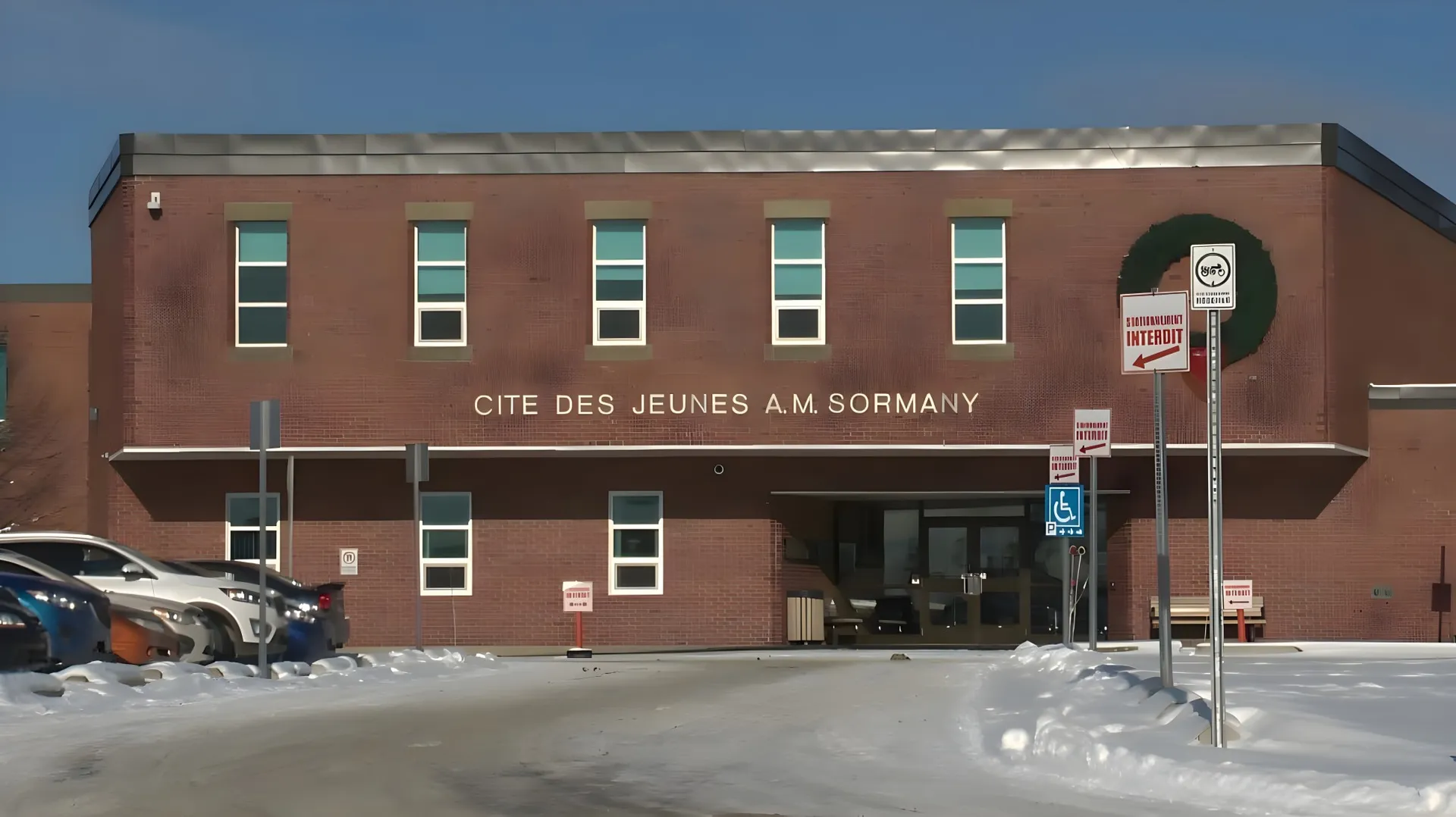 L'edificio in mattoni della Cité des Jeunes A.-M.-Sormany con grandi finestre lungo una strada coperta di neve.