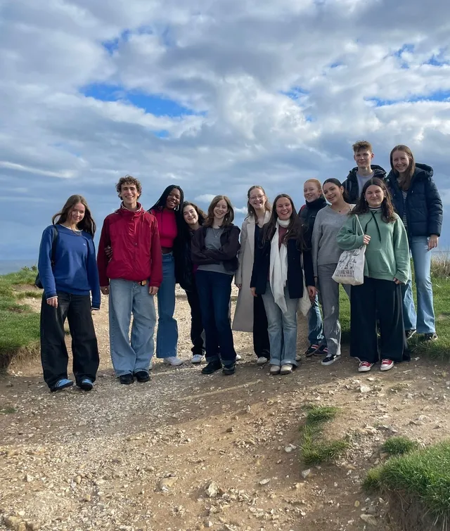 Grupo de alumnos posando en un sendero costero bajo un cielo de nubes