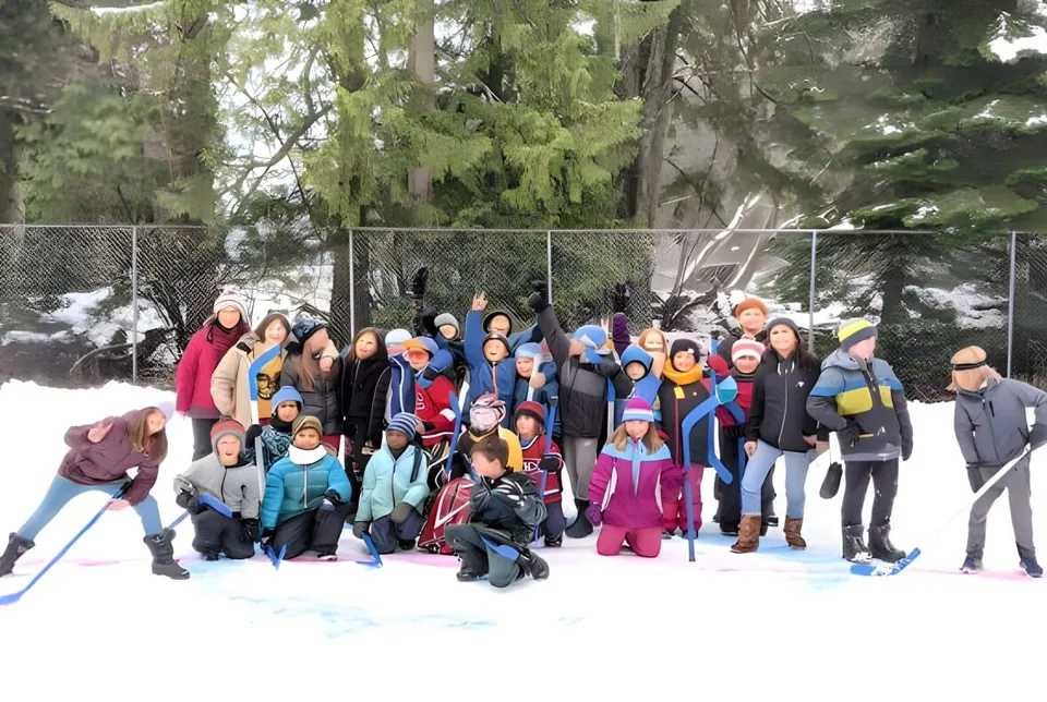 Un gruppo di studenti della École des Sentiers-Alpins si trova nell'area esterna innevata sotto gli alberi.