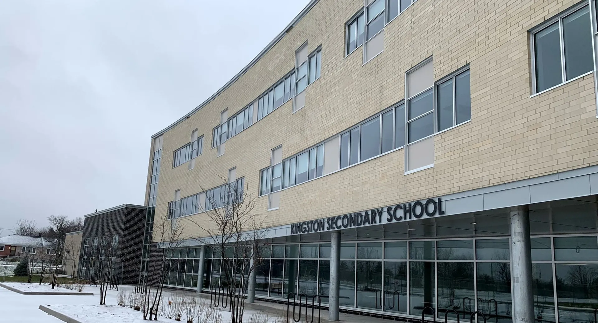L'edificio in mattoni a più piani della Kingston Secondary School si erge davanti a un paesaggio innevato.