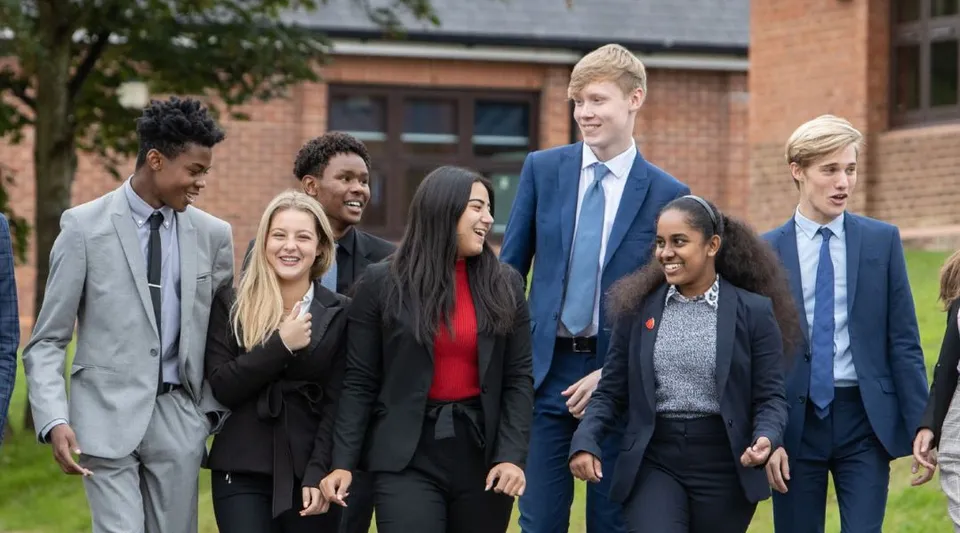 Un gruppo di studenti della St. Mary Catholic Secondary School cammina insieme nel campus della scuola, con un edificio in mattoni e alberi sullo sfondo.