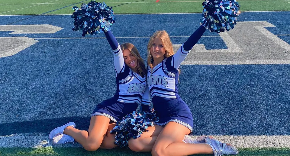 Due cheerleader eseguono una coreografia in uniformi blu e bianche sul campo sportivo del Santa Barbara Unified School District.