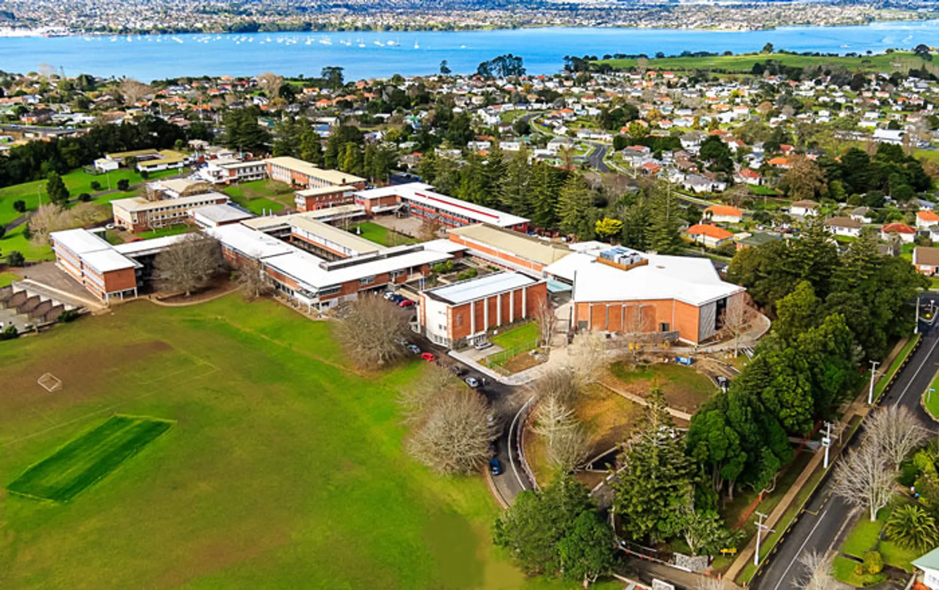 L'ampio campus del Sacred Heart College è immerso nel verde con vista su uno specchio d'acqua sullo sfondo.