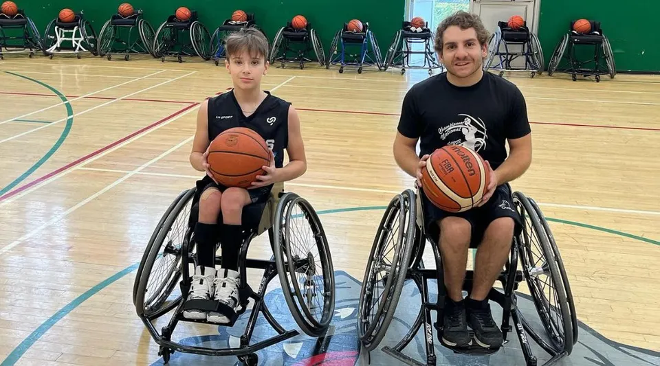 Due studenti in sedia a rotelle giocano a basket sul campo della Macdonald High School.