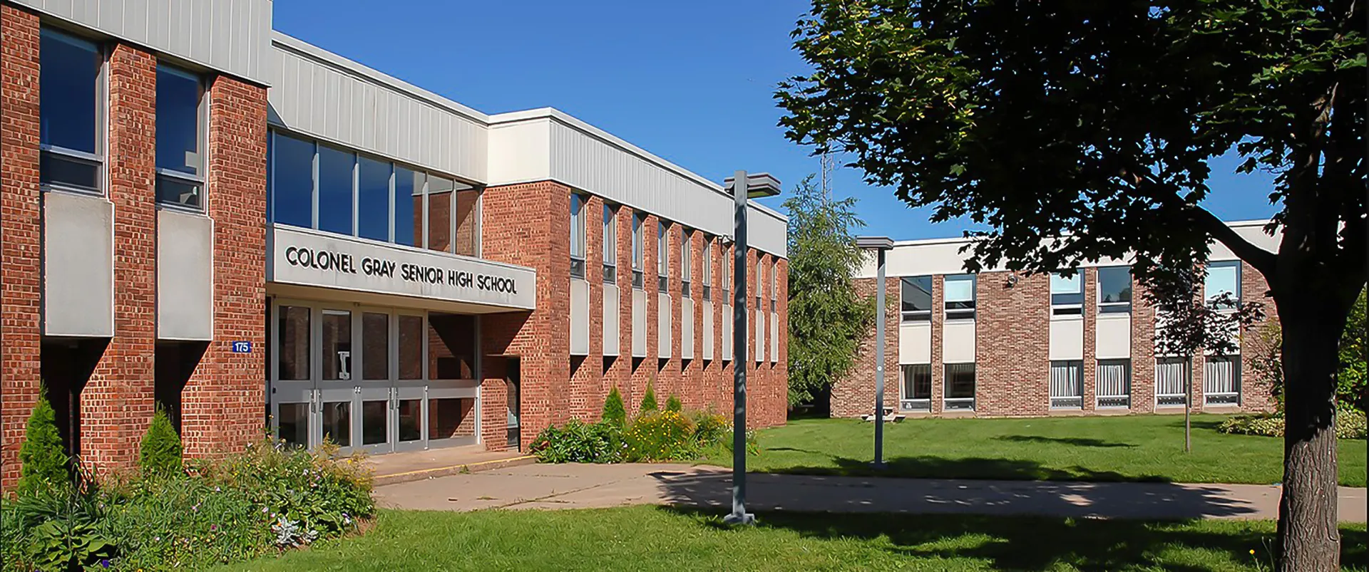 L'edificio in mattoni a più piani della Colonel Gray High School con ampie finestre e un prato in primo piano.