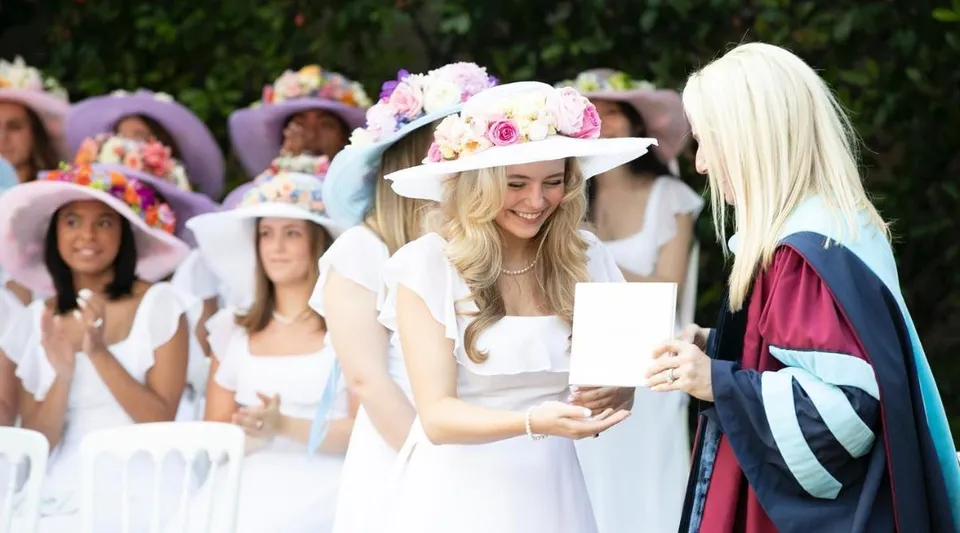 Una studentessa della The Hockaday School con un cappello decorato con fiori riceve un diploma durante la cerimonia.