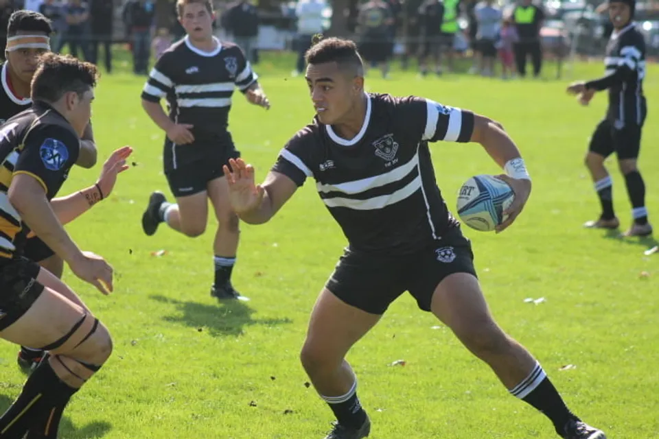 Un gruppo di giocatori di rugby in uniformi bianche e nere disputa una partita sul campo di gioco del Wesley College.