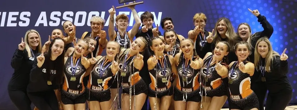 Un gruppo della Gladstone High School posa in abbigliamento sportivo con medaglie e un trofeo.