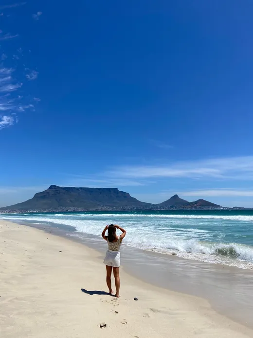 Ragazza in riva all'oceano guarda la Table Mountain di Città del Capo durante un anno all'estero in Sudafrica
