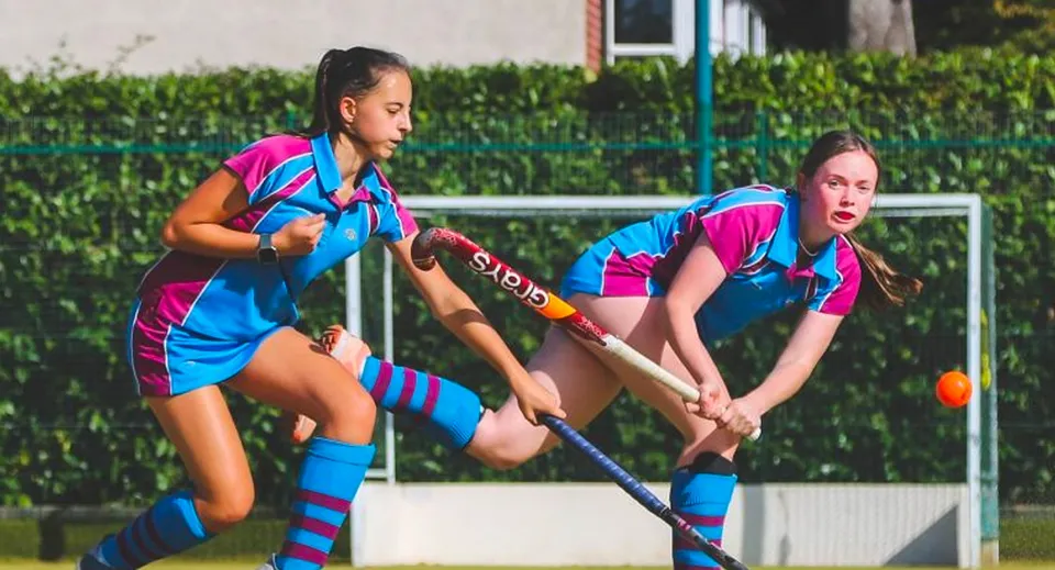 Due studentesse della Burgess Hill Girls giocano una partita di hockey su prato su un campo con porta.